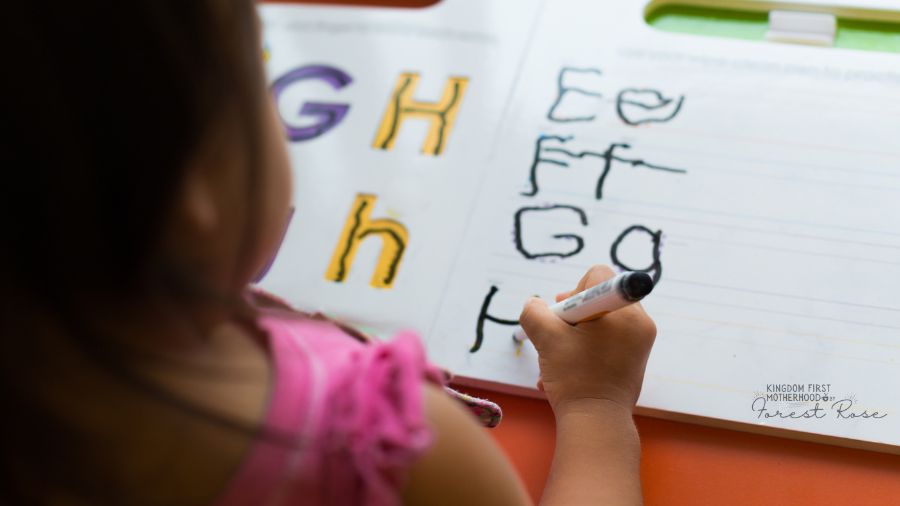 young child writing ABCs