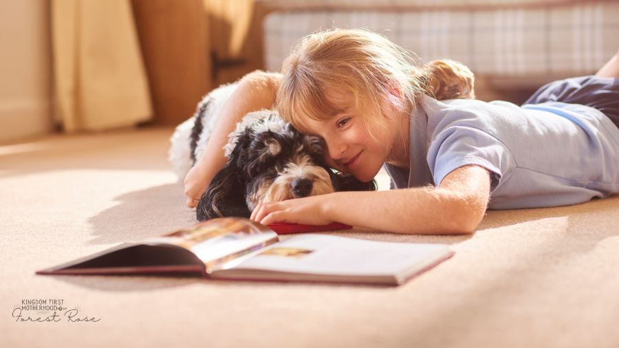 Little girl reading and snuggling her dog