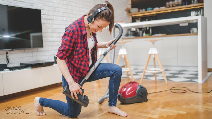 woman making cleaning more fun by playing an air guitar on vacuum