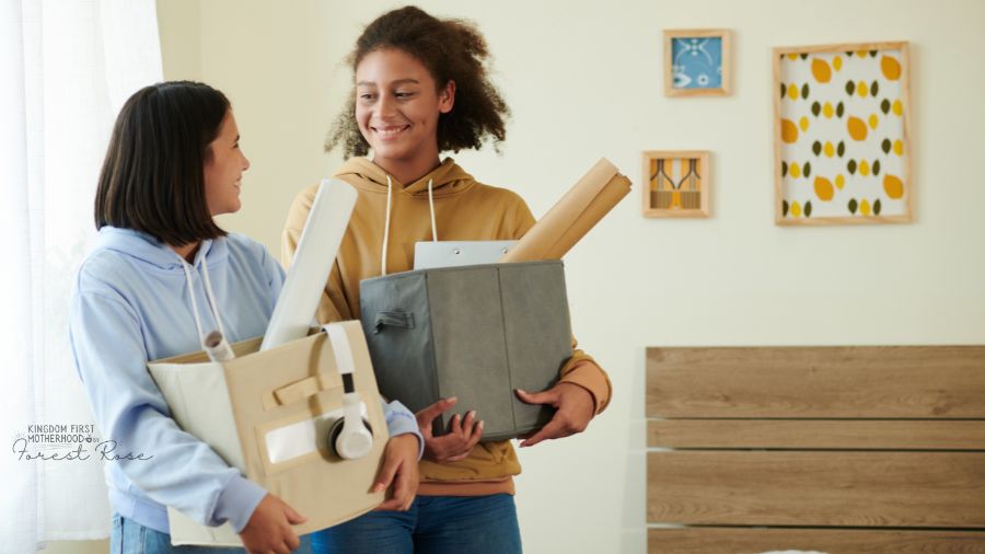 Roommates moving in and smiling with boxes