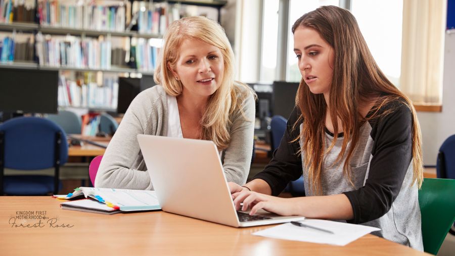 Mom helping daughter on laptop - financial responsibility